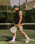 Model wearing Cuera Active Gilet in Black, lifestyle action shot on the padel court