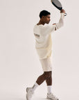 Model wearing Cuera Active Light Weight T-Shirt in Off White/Walnut, lifestyle action shot on the padel court