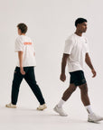 Model wearing Cuera Offcourt Logo T-Shirt in Off White w. Orange, lifestyle action shot on the padel court