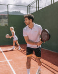 Model wearing Cuera Oncourt Made Polo ss in White, lifestyle action shot on the padel court