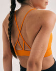 Model wearing Cuera Oncourt Soft Bra Top in Orange, close-up detail on model