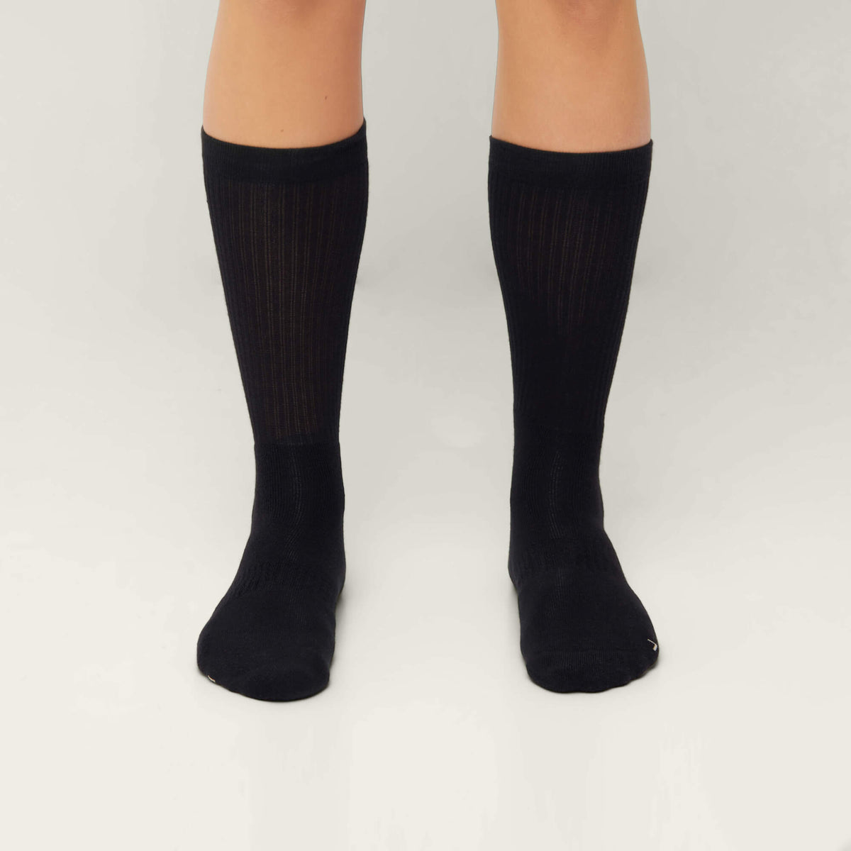Model wearing Cuera 2-pack Bandeja Padel Socks in Black/Sand, back studio view