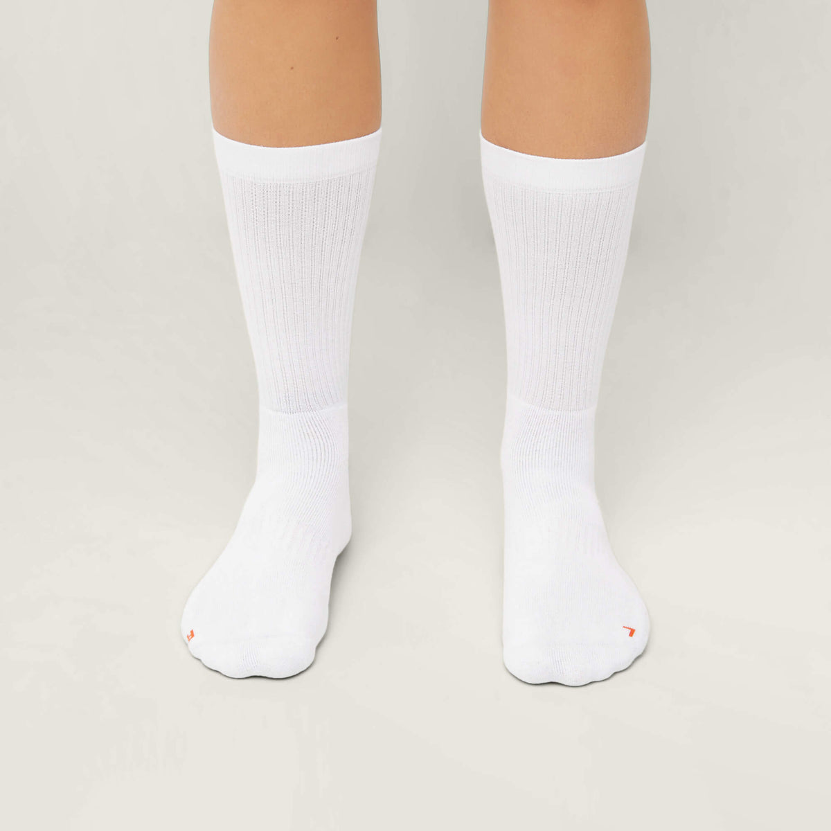 Model wearing Cuera 2-pack Bandeja Padel Socks in White/Orange, back studio view