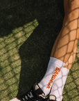 Model wearing Cuera 2-pack Bandeja Padel Socks in White/Orange, close-up detail on model