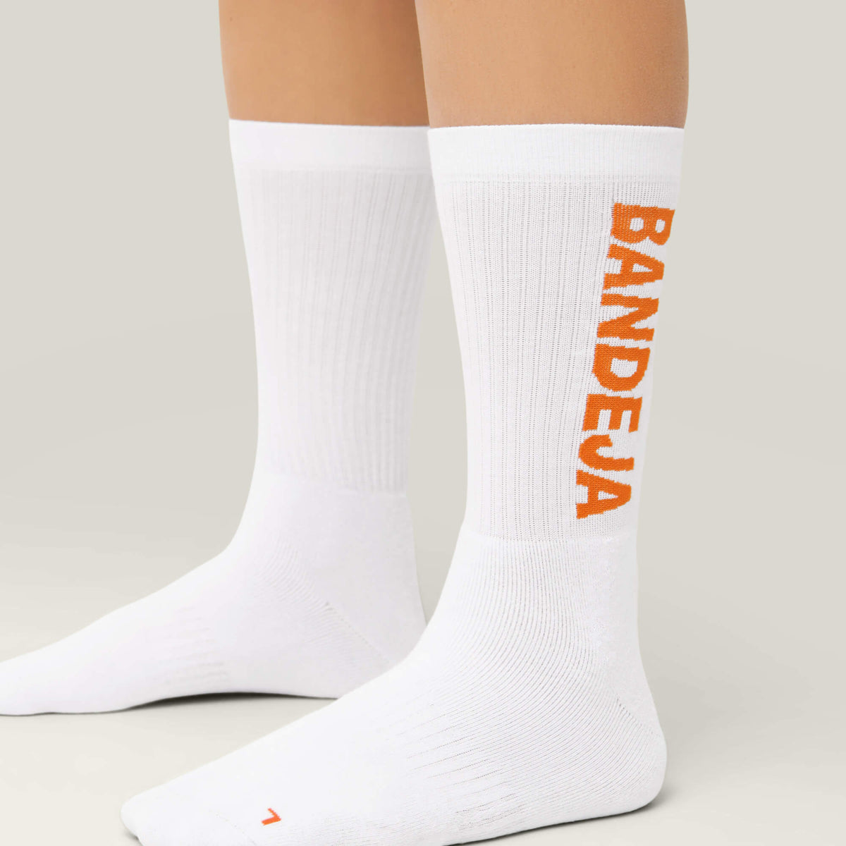 Model wearing Cuera 2-pack Bandeja Padel Socks in White/Orange, front studio view
