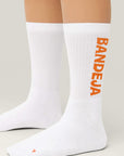 Model wearing Cuera 2-pack Bandeja Padel Socks in White/Orange, front studio view