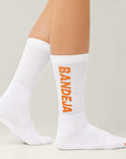 Model wearing Cuera 2-pack Bandeja Padel Socks in White/Orange, front studio view