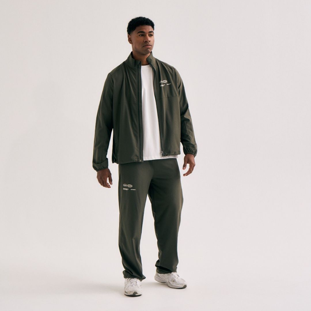 Model wearing Cuera Active Cuera Track Pants in Army, back studio view