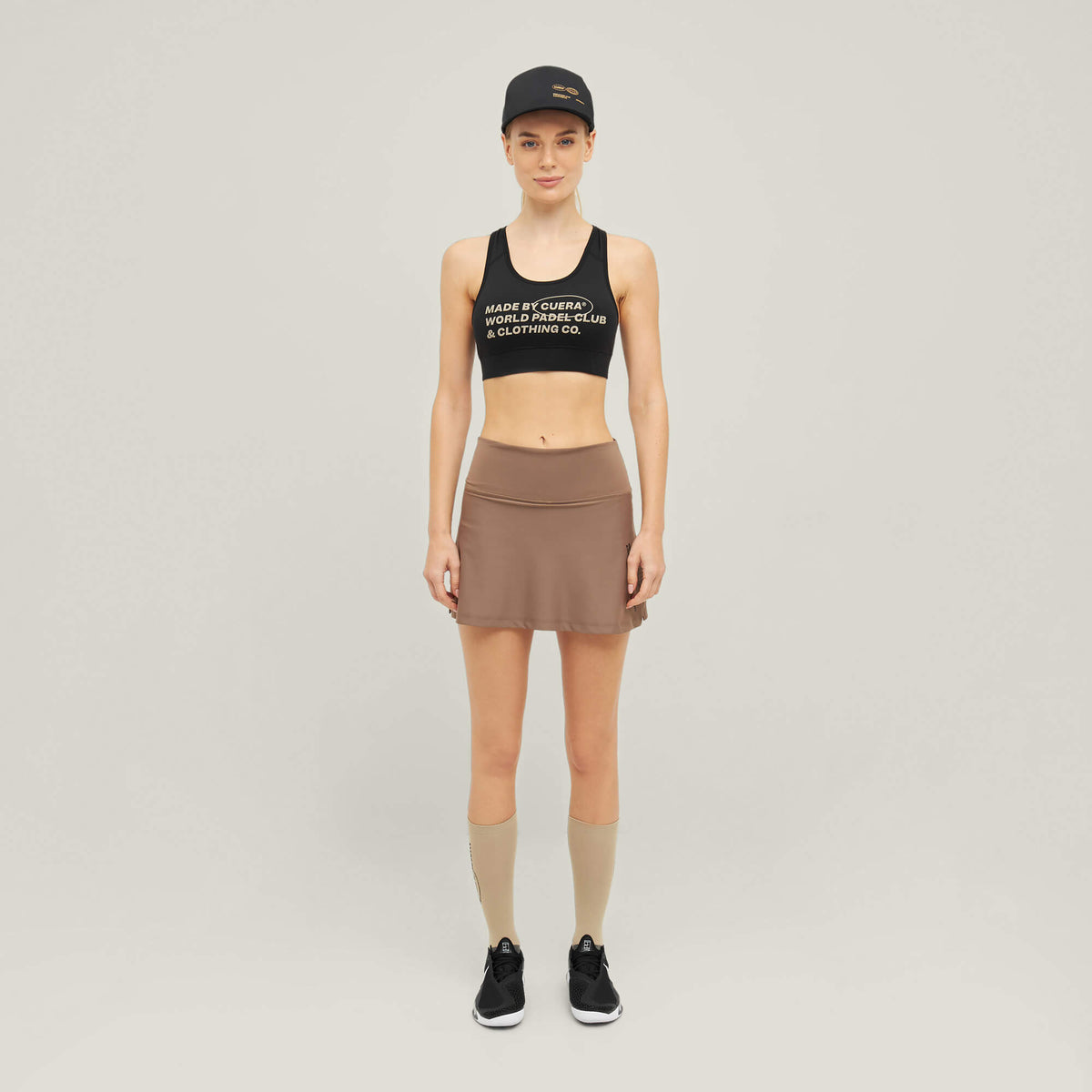 Woman wearing Cuera Active Made Bra in Black with matching skirt, front studio view