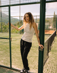 Model wearing Cuera Active Rib Tank Top in Off White, lifestyle action shot on the padel court