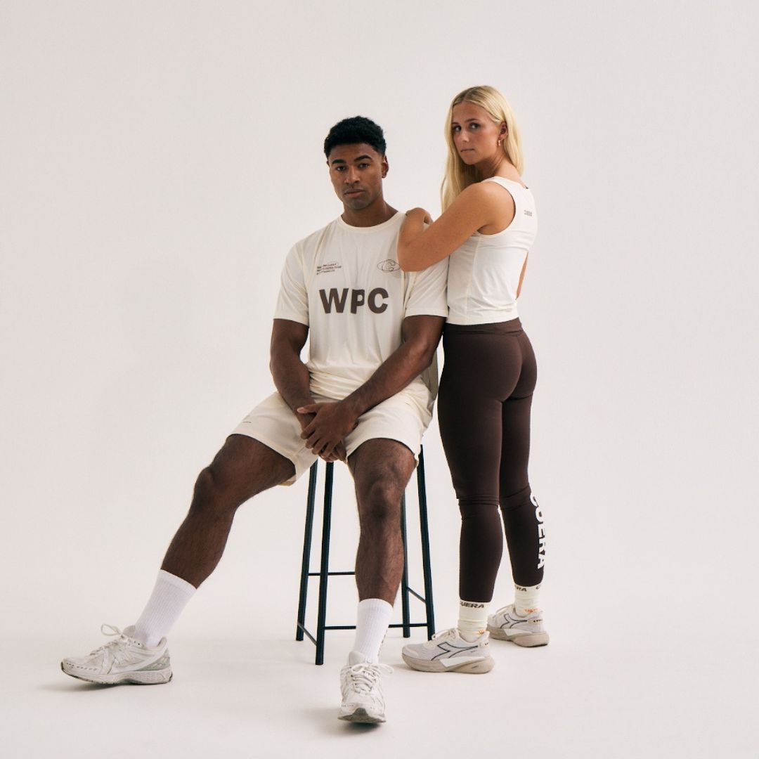 Model wearing Cuera Active WPC Light Weight T-Shirt in Off White/Walnut, lifestyle action shot on the padel court
