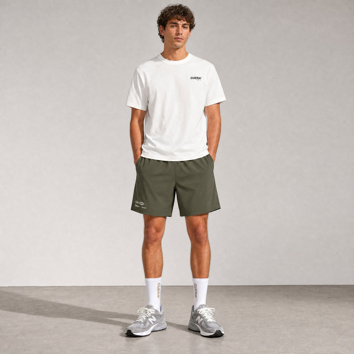 Man wearing Cuera Mens Active Globe Shorts in Army, front studio view