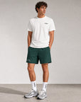 Man wearing Cuera Mens Active Globe Shorts in Court Green, lifestyle action shot on the padel court