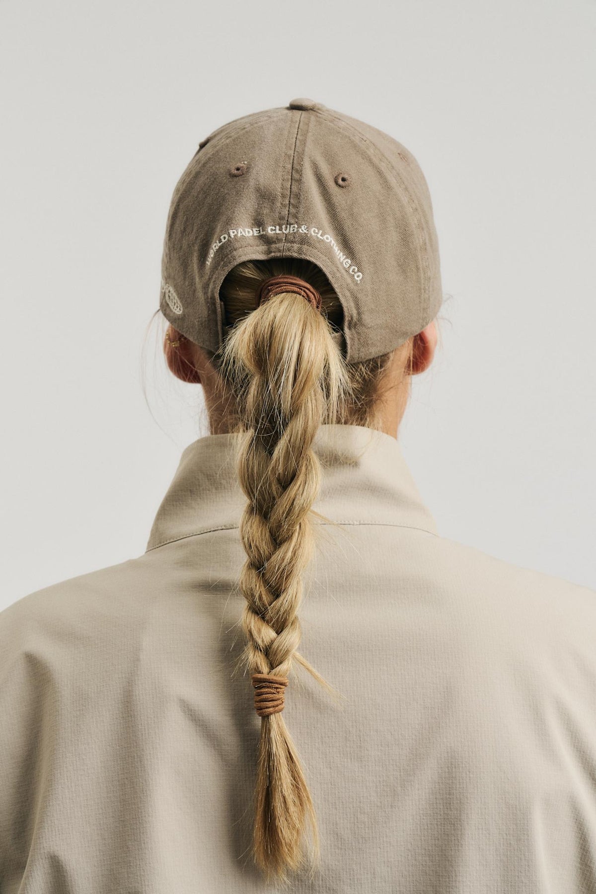 Model wearing Cuera Offcourt Cuera Cap in Walnut, back studio view