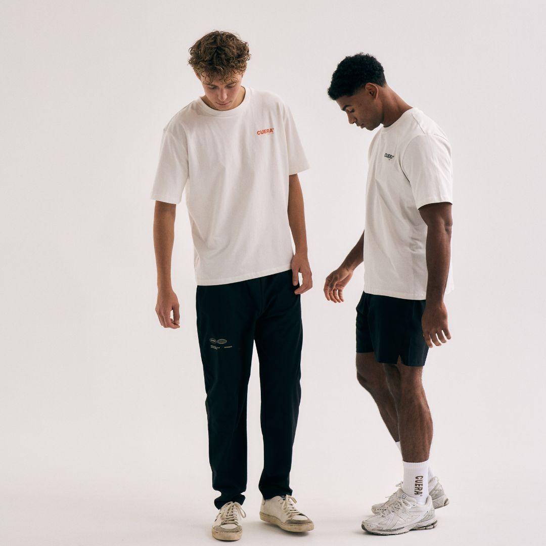 Model wearing Cuera Offcourt Logo T-Shirt in Off White w. Orange, lifestyle action shot on the padel court