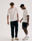 Model wearing Cuera Offcourt Logo T-Shirt in Off White w. Orange, lifestyle action shot on the padel court