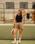 Model wearing Cuera Oncourt Cropped Tank Top in Black, lifestyle action shot on the padel court