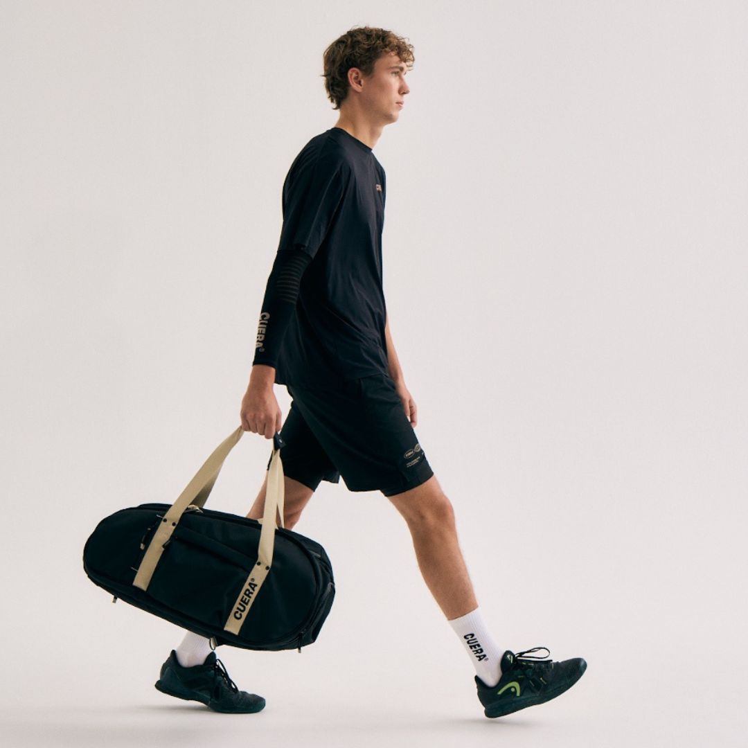 Model with Cuera Oncourt Medium Padel Bag in Black, lifestyle action shot on the padel court